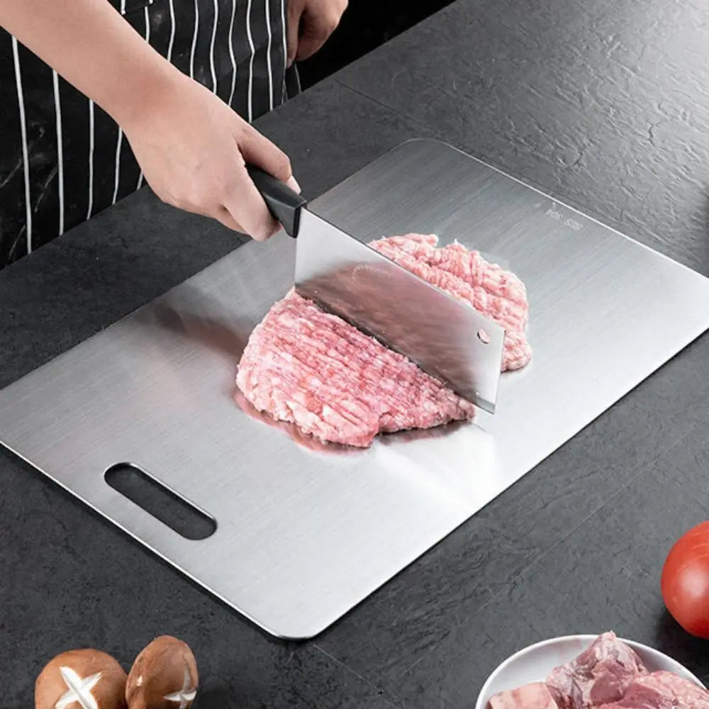 Brushed metal chopping board detail with a cleaver and finger-grip handle cutout.