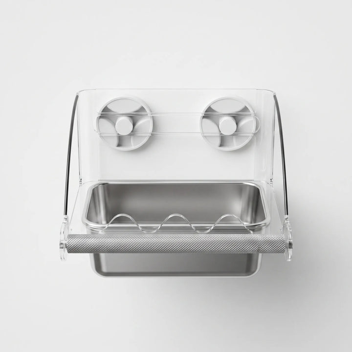 Front view of the clear acrylic feeder with two suction cups, a textured metal perch bar and a stainless steel tray. 1