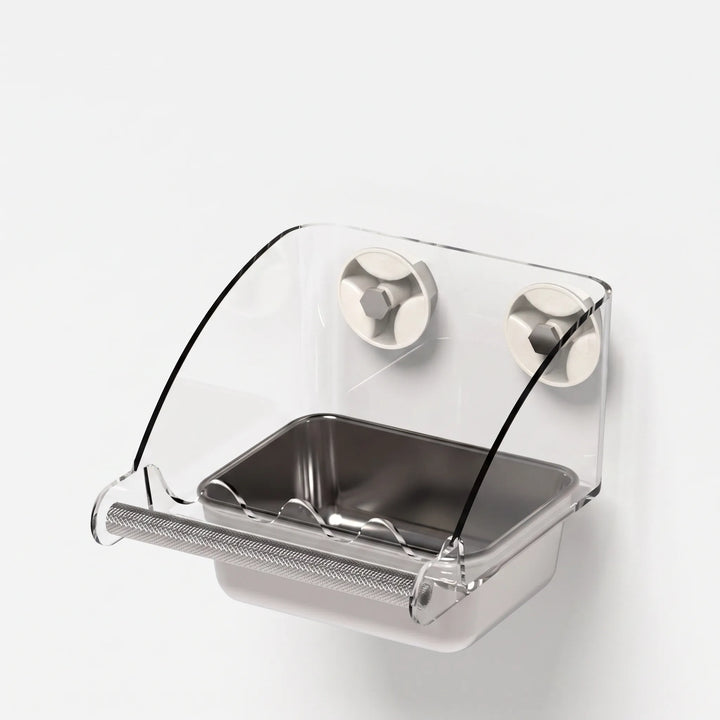Three-quarter view of the empty feeder with curved clear cover, two suction mounts, perch bar and rectangular steel tray. 5