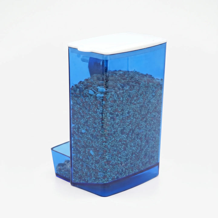 Blue-tinted seed feeder with white lid, filled with seed and seen from the side, with the small tray at the lower left. 1