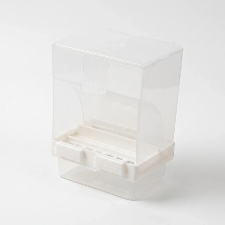 Angled view of the empty feeder from the front, showing the white feeding slots and the clear tray underneath. 4