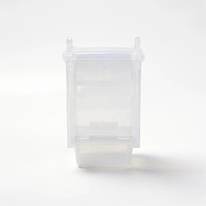 Empty clear plastic cage feeder with hanging hooks and a seed tray at the bottom, shown alone on a white background. 1