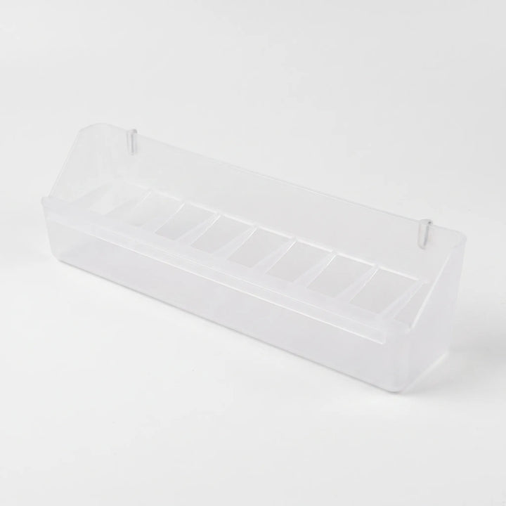 Empty long clear plastic feeder angled from above, showing the row of narrow compartments and two small hanging pegs. 7