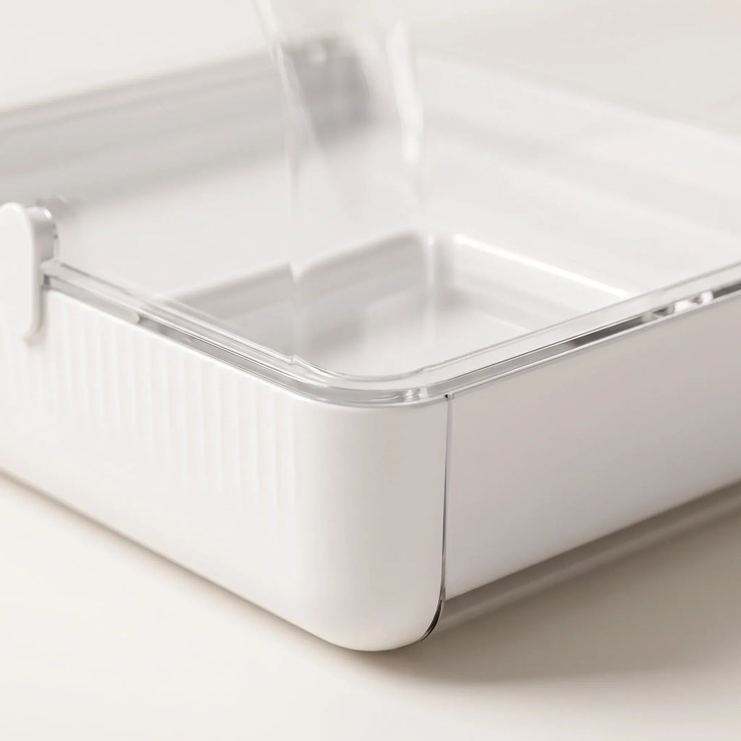 Close-up of the white ribbed tray corner and clear rim, showing the small inner dish and side latch. 3