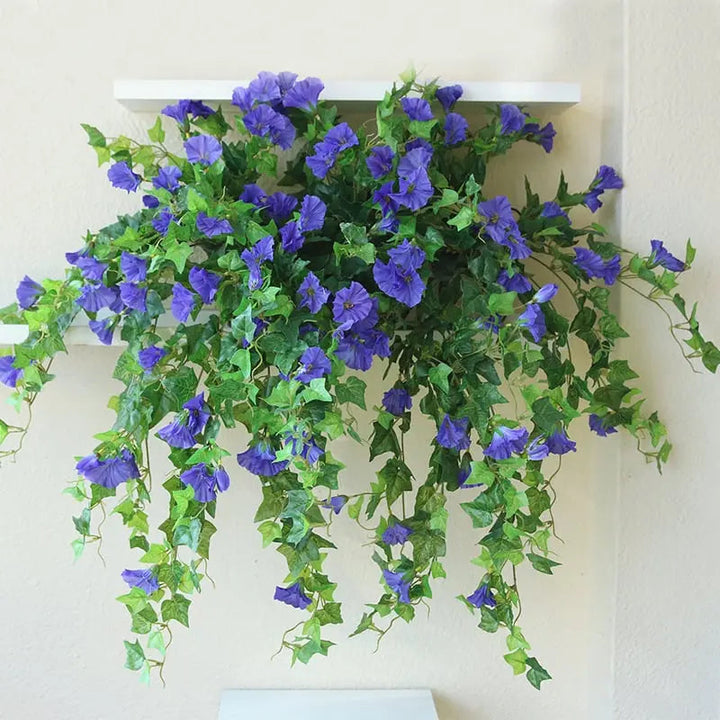 Purple-blue faux morning glory vines with bright green leaves draping from a white wall shelf in a long cascade.