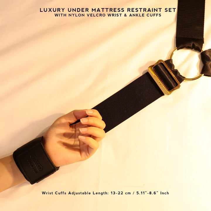 Detail of a hand in a black wrist cuff joined to a wide black strap with a gold-tone buckle and ring