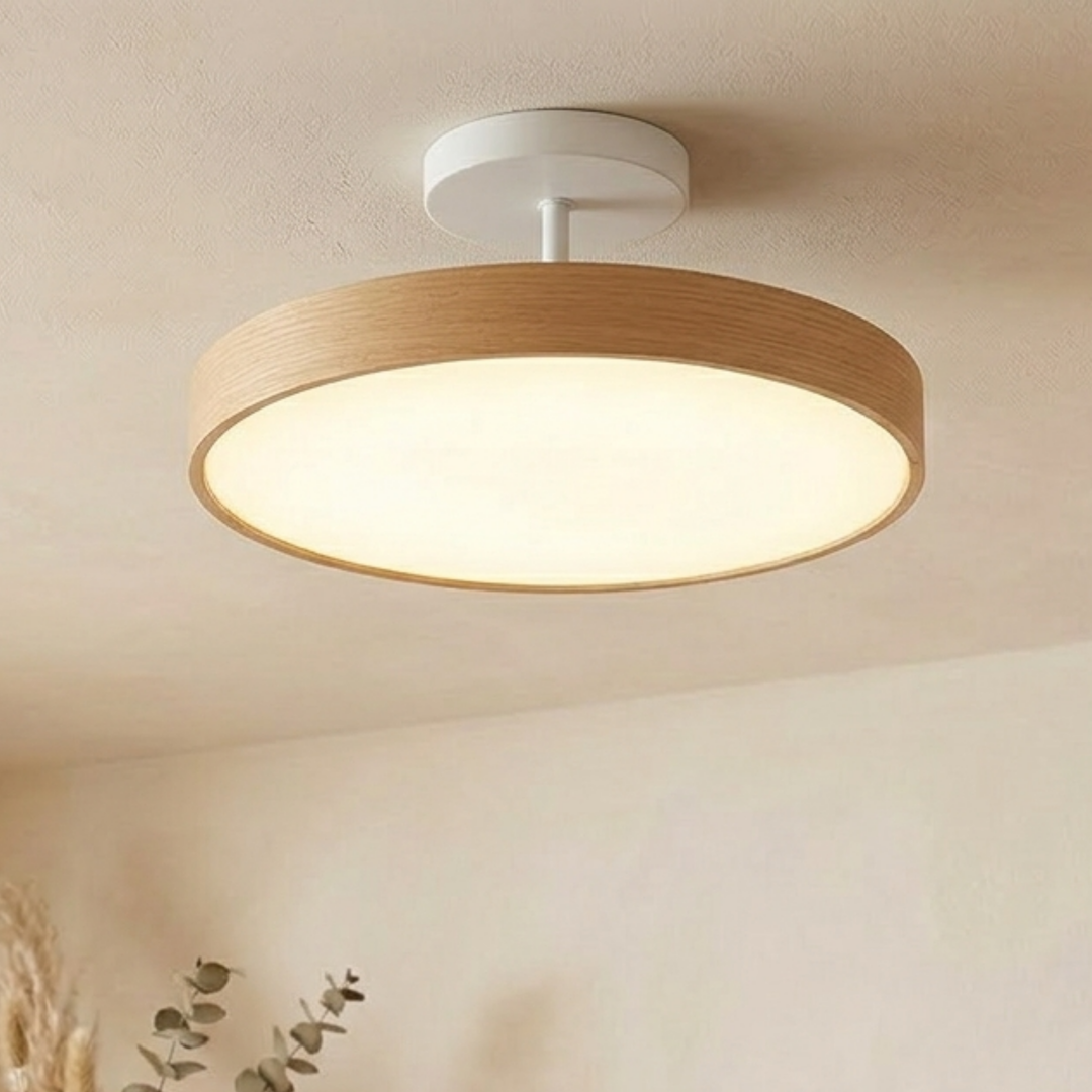 Light wood-grain disc ceiling light with a white round canopy and stem, glowing softly on a cream ceiling.