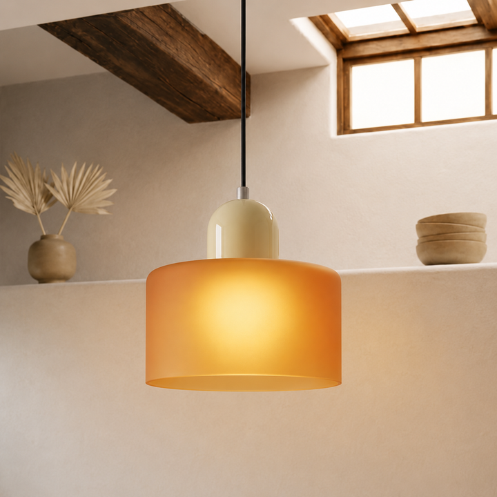 Lit pendant lamp with a frosted amber-orange drum shade and cream dome cap, glowing warmly in a rustic room. 42