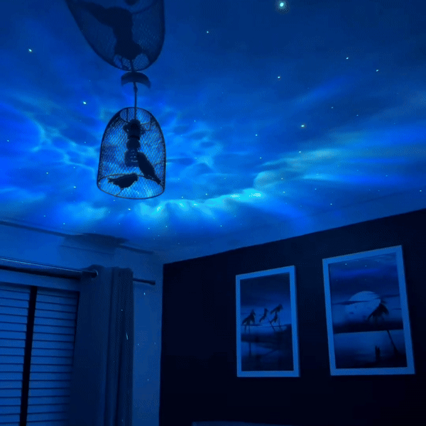 Blue nebula and scattered stars projected across a bedroom ceiling and wall.