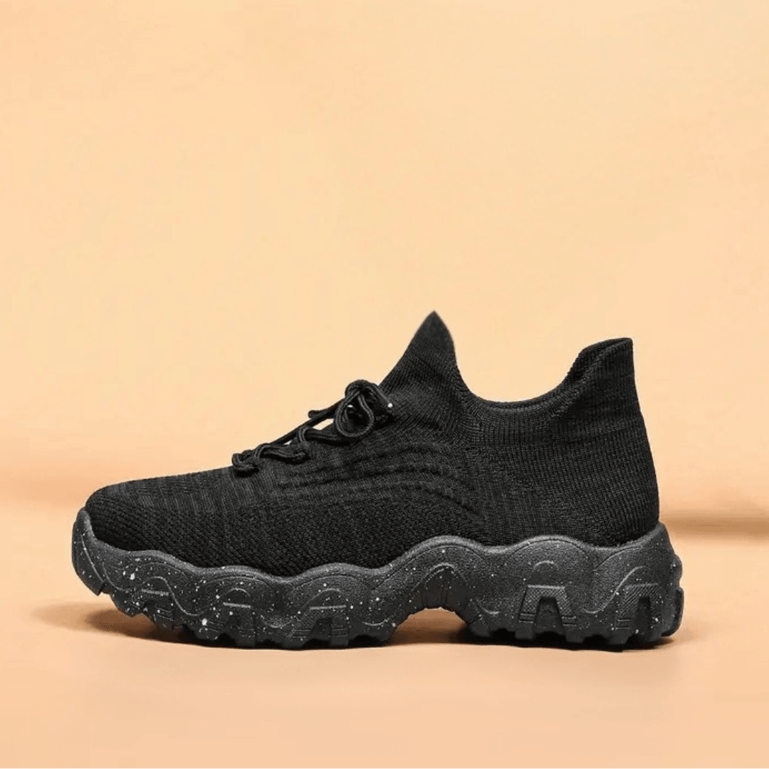 Another view of an all-black knit sneaker with laces and a chunky speckled black sole.