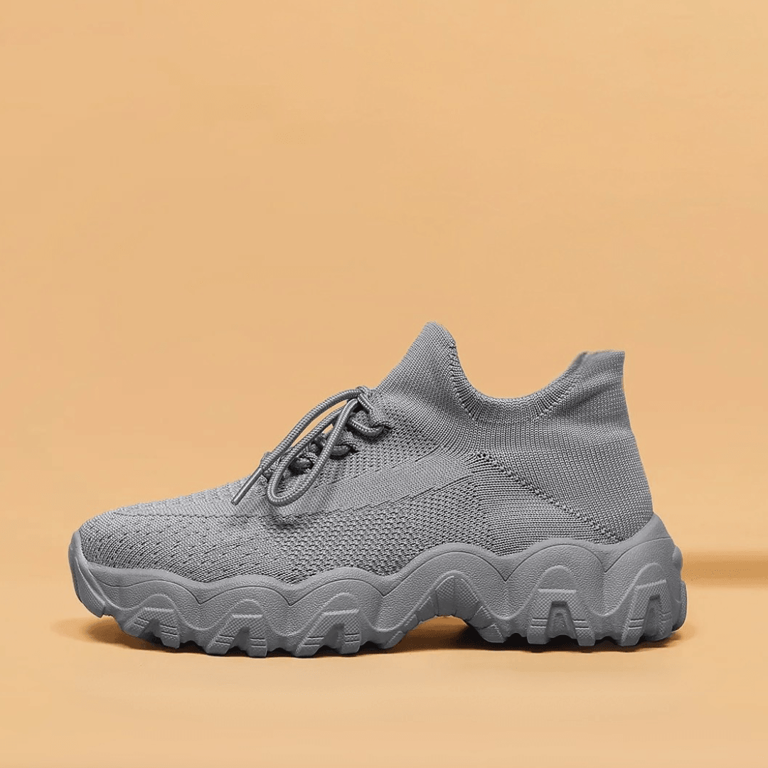 Side view of a solid gray knit sneaker with a sock-style collar, laces and a thick wavy tread sole. 43