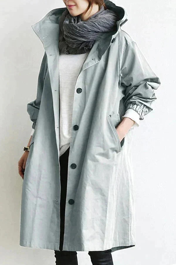Pink waterproof hooded trench coat front view with a scarf and black pants