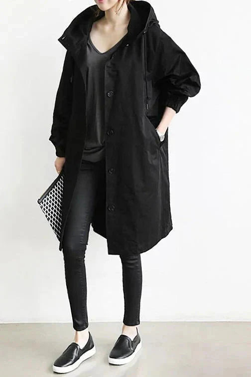 Pink waterproof hooded trench coat in black, worn buttoned with black pants