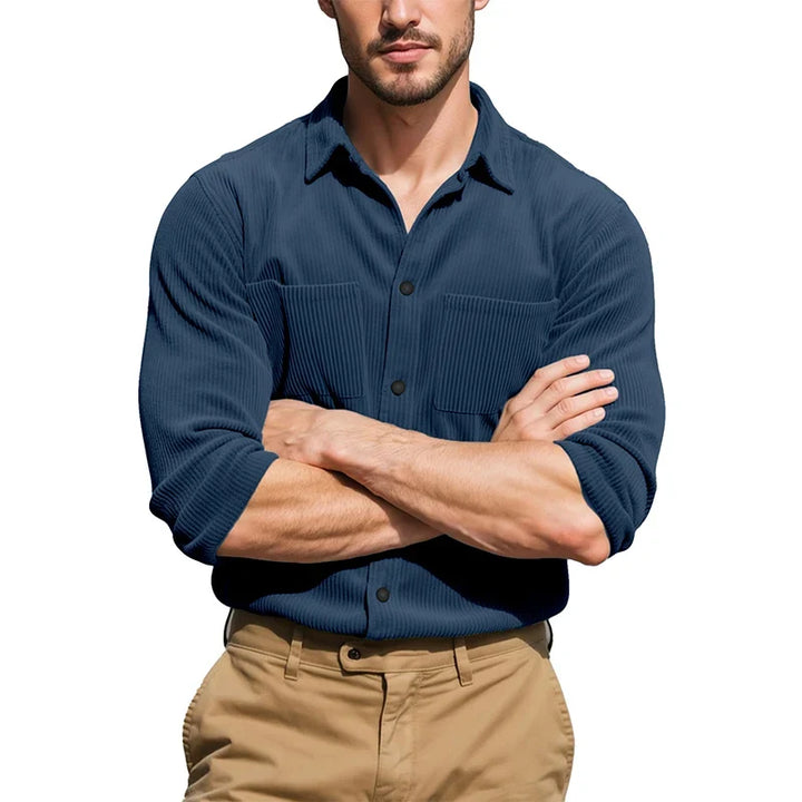 Model with arms crossed in a navy blue ribbed button shirt with sleeves rolled, worn with khaki pants 4