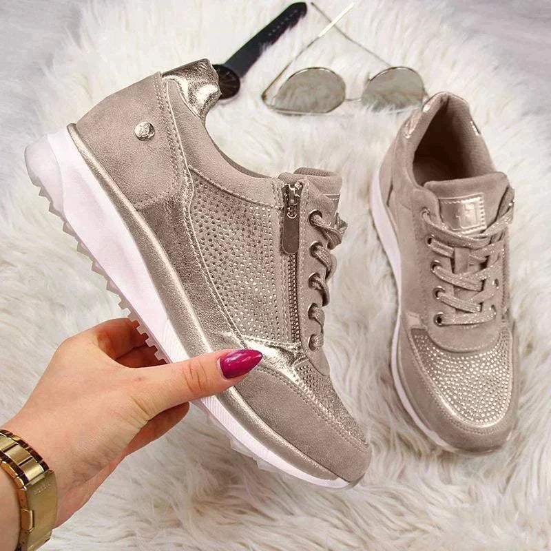 Another view of a taupe sneaker showing its side zipper and perforated panel, with the second shoe and accessories.
