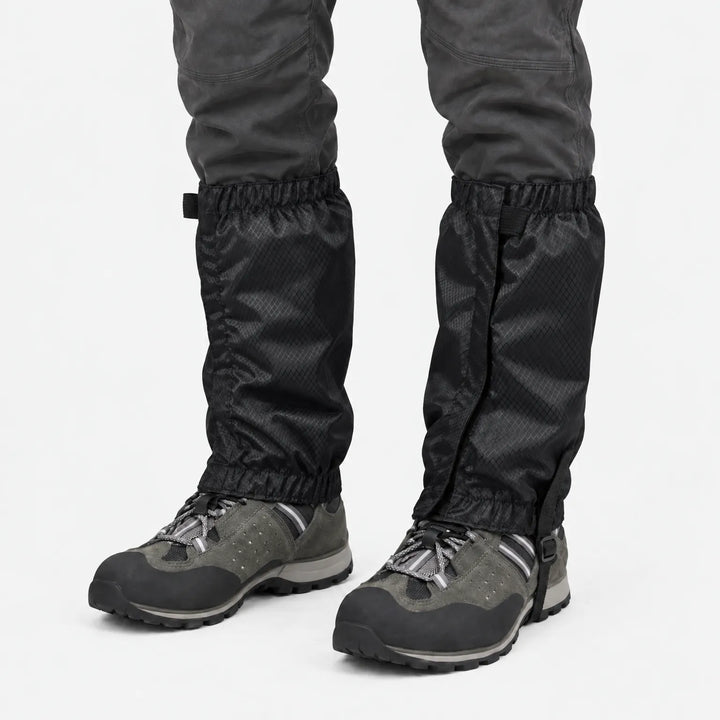 Front view of black ripstop gaiters with hook-and-loop closure and instep strap, worn over gray hiking shoes against a white background. 9