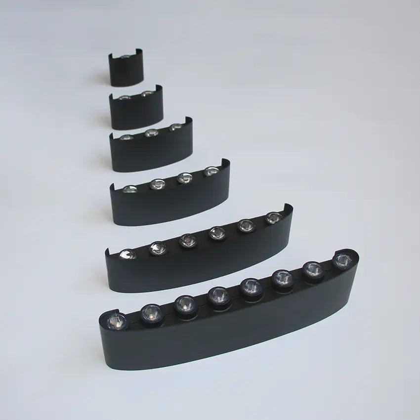 Six unmounted black Skøle wall light fixtures lined up from smallest to largest