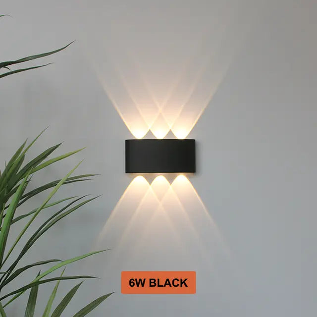Black Skøle wall light fixture detail with three lens openings glowing warm and casting overlapping beams