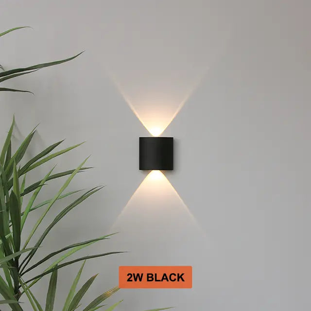 Black Skøle wall light fixture detail on a gray wall shining warm up-and-down beams