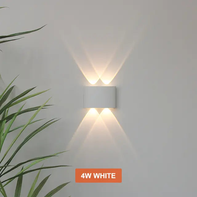 White Skøle wall light fixture detail with two lens openings per side projecting crossing warm beams