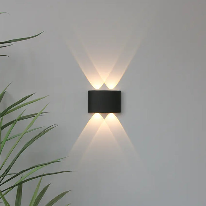 Black Skøle wall light fixture detail with two lens openings and crossing warm triangular beams