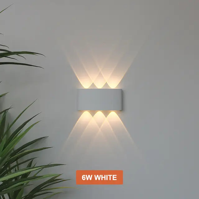 White Skøle wall light fixture detail with three openings per side projecting overlapping warm beams