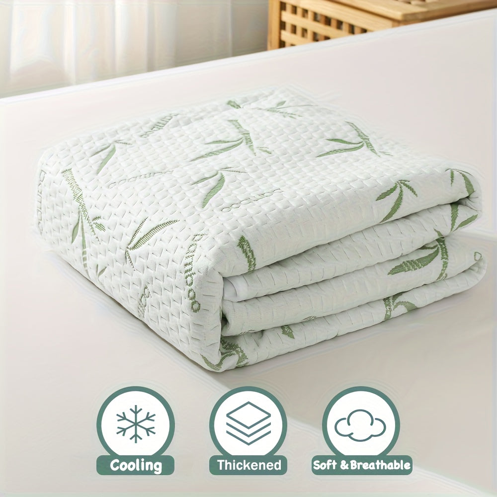 Folded mattress protector with a textured white surface and green bamboo print, shown on a bed with feature icons below. 2
