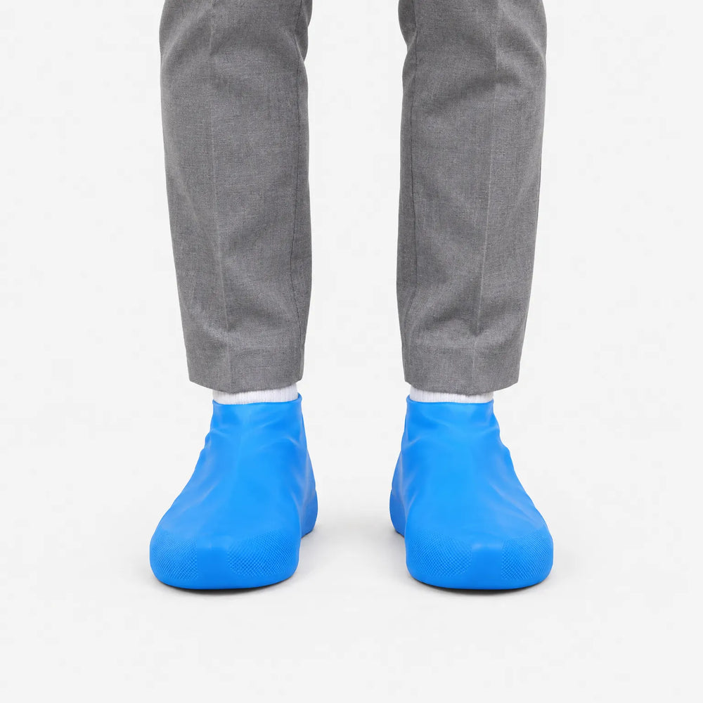 Front view of blue shoe covers worn over shoes with a white sock, against a plain white background. 2