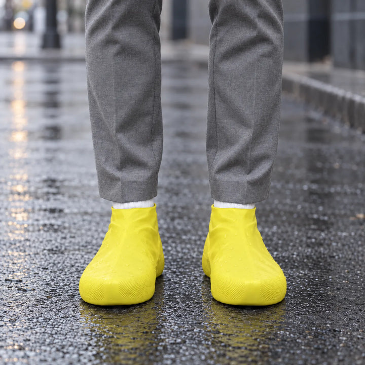 Yellow shoe covers worn on a wet city street, with water droplets beaming on the surface, front view. 3