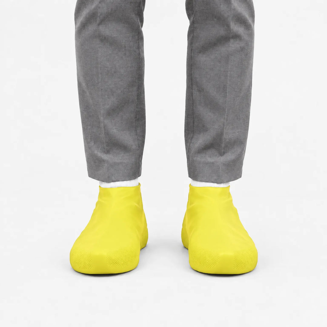 Front view of yellow shoe covers worn with gray trousers and white socks against a plain white background. 7