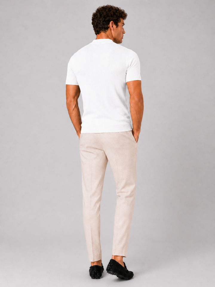 Back view of the men's white ribbed mock neck tee with cream trousers and black loafers.
