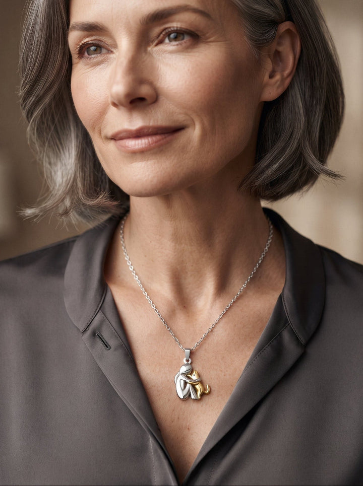 Woman with a gray bob in a dark satin blouse wearing the pendant, a silver-tone figure with a gold-tone pet. 10