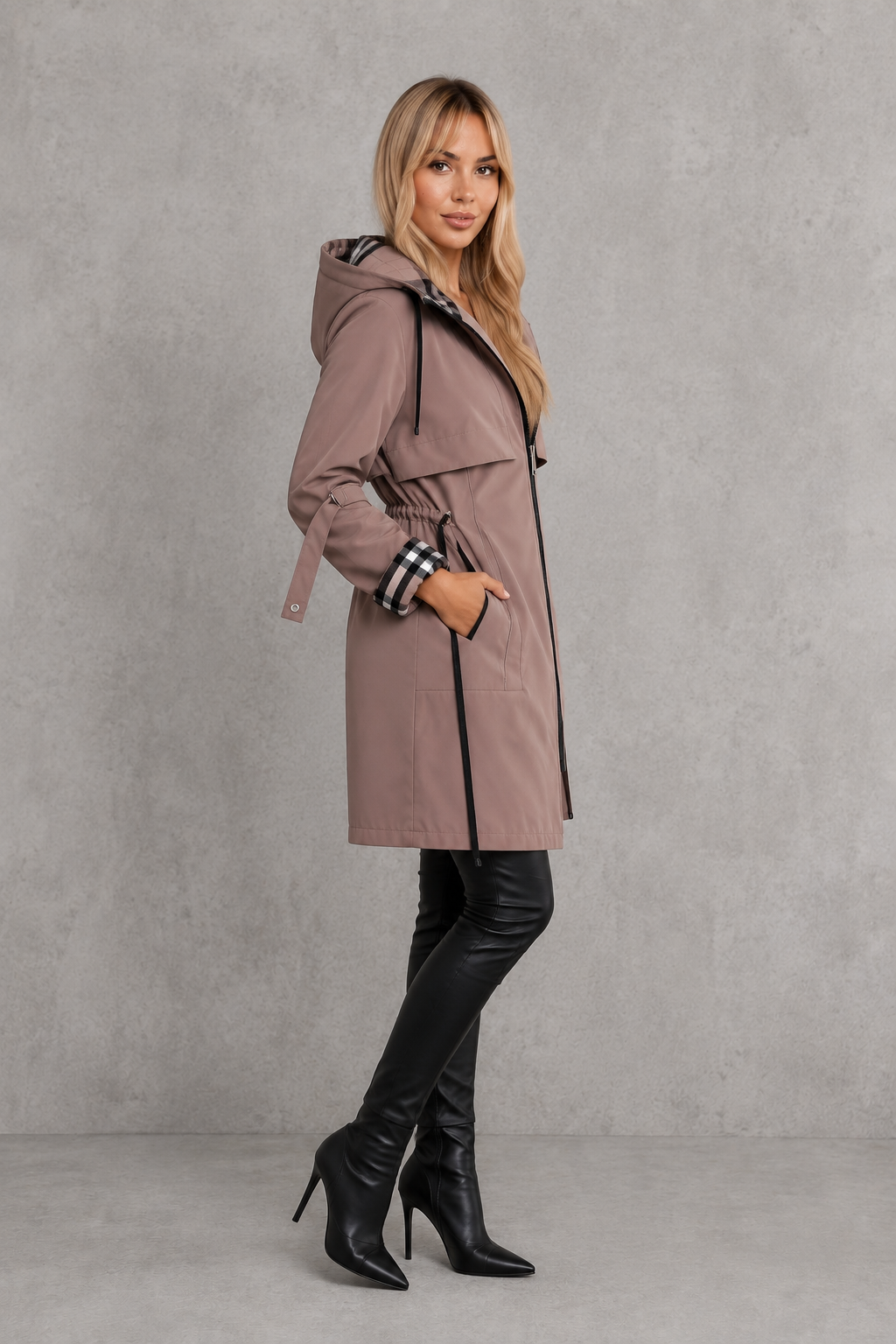 Side view of a model in the mauve hooded coat with cinched drawstring waist, cuff strap and black piping, worn with black boots. 4