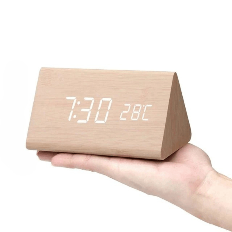 Light natural wood triangular clock with white LED digits resting on an open palm.