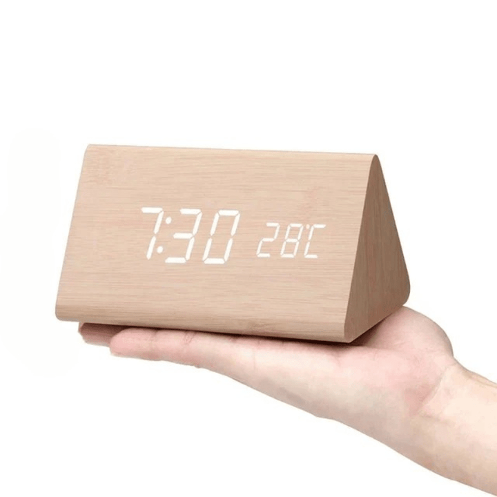 Light natural wood triangular clock with white LED digits resting on an open palm.