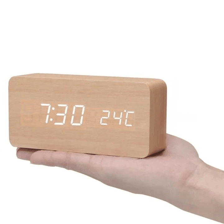 Light natural wood rectangular clock with white LED digits held on an open hand.