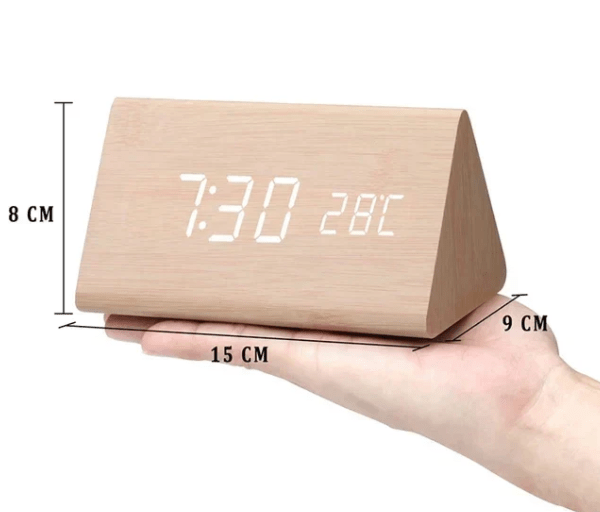 Light bamboo-toned triangular clock held in a palm with arrows marking its height, width and depth.