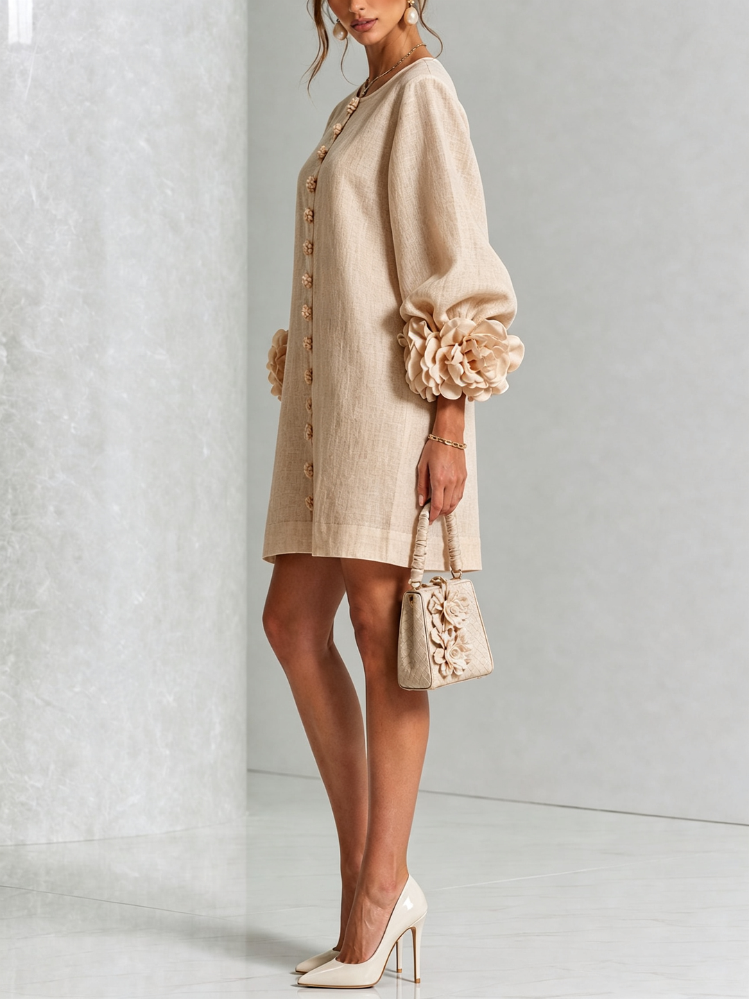 Side view of the beige dress worn with white heels and a small handbag, showing the balloon sleeve and flower cuff. 24