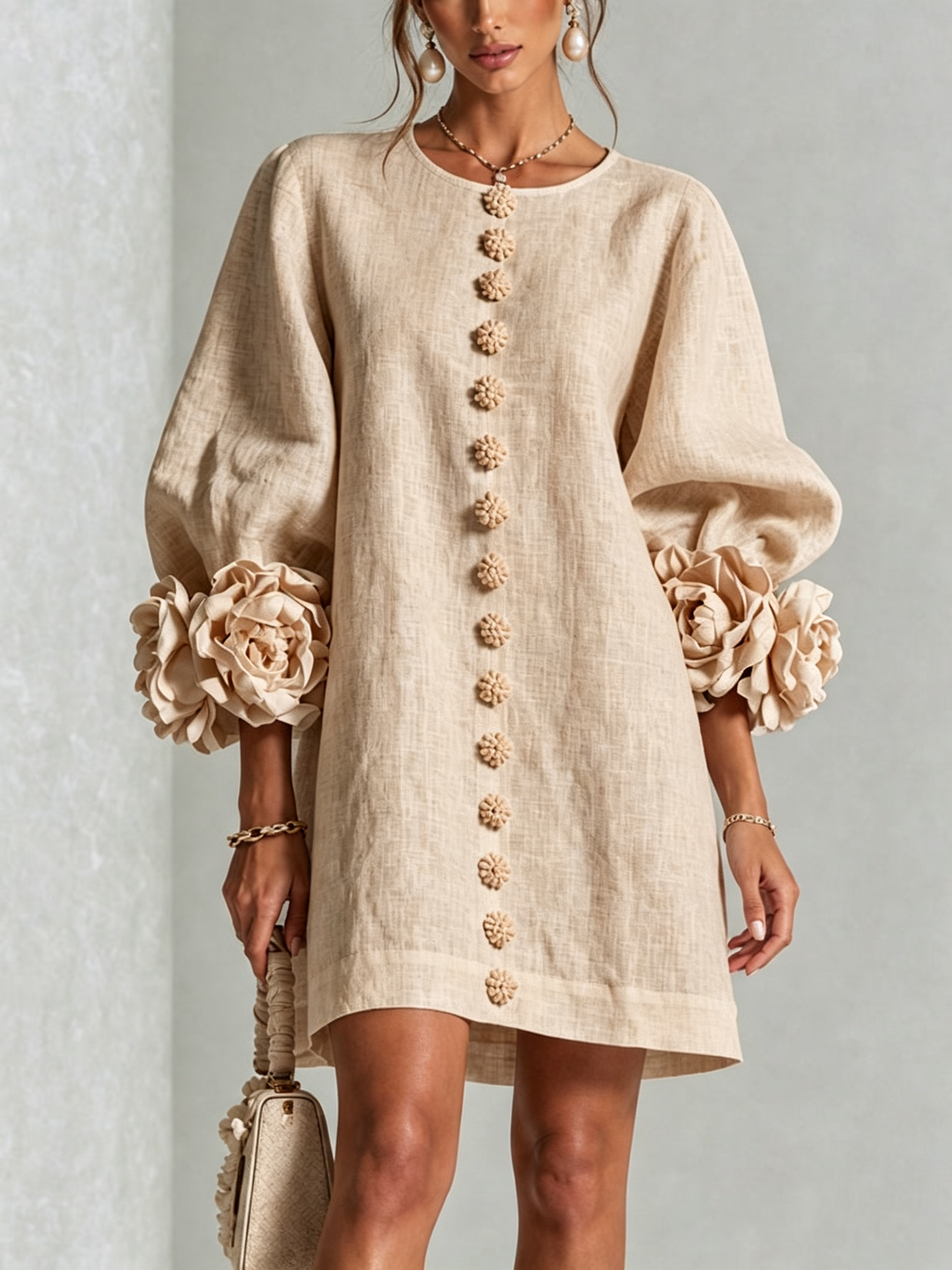 Beige linen blend shirt dress on a model, front view, with flower buttons down the front and big rose cuffs on the sleeves. 27