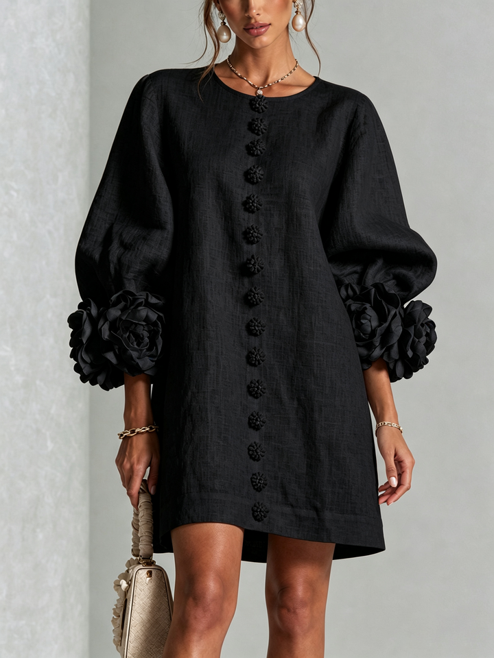Black linen dress, front view, with matching flower buttons and rose-trimmed puffed sleeves.