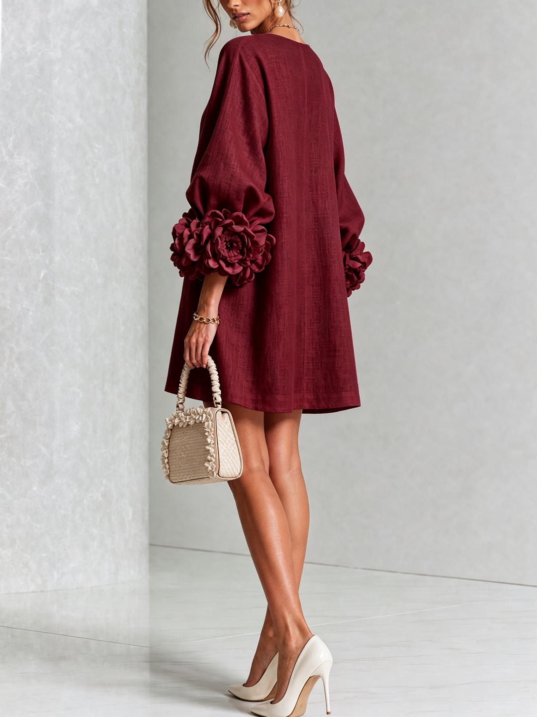 Back view of the burgundy dress on a model, showing the plain back and oversized flower cuffs on the sleeves. 37