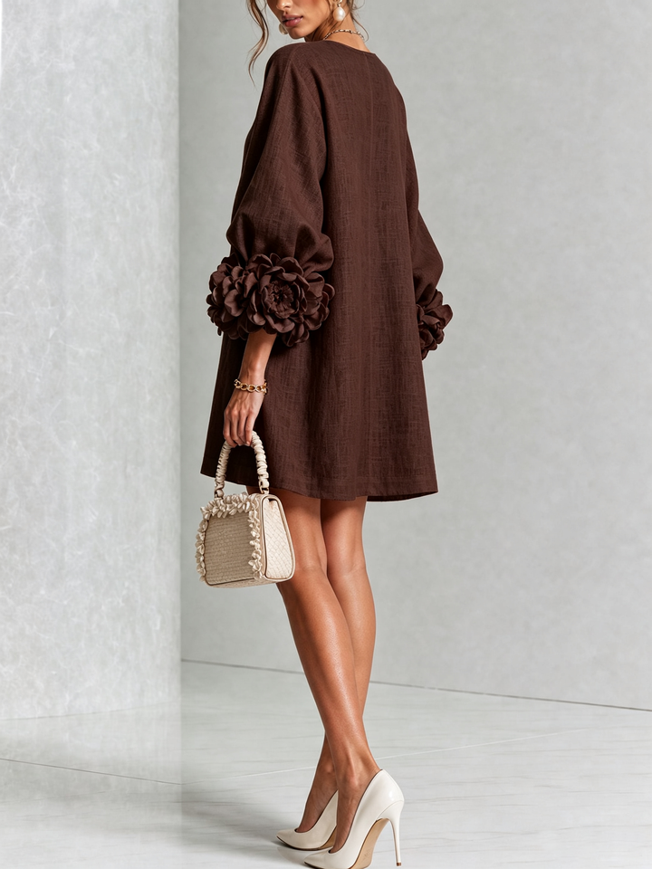 Back view of the brown dress on a model, showing the plain back and large flower cuffs. 29