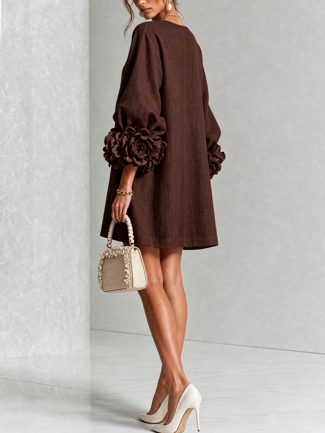 Brown dress on a model from the back, showing the plain back, relaxed fit and large rose cuffs on the sleeves. 33