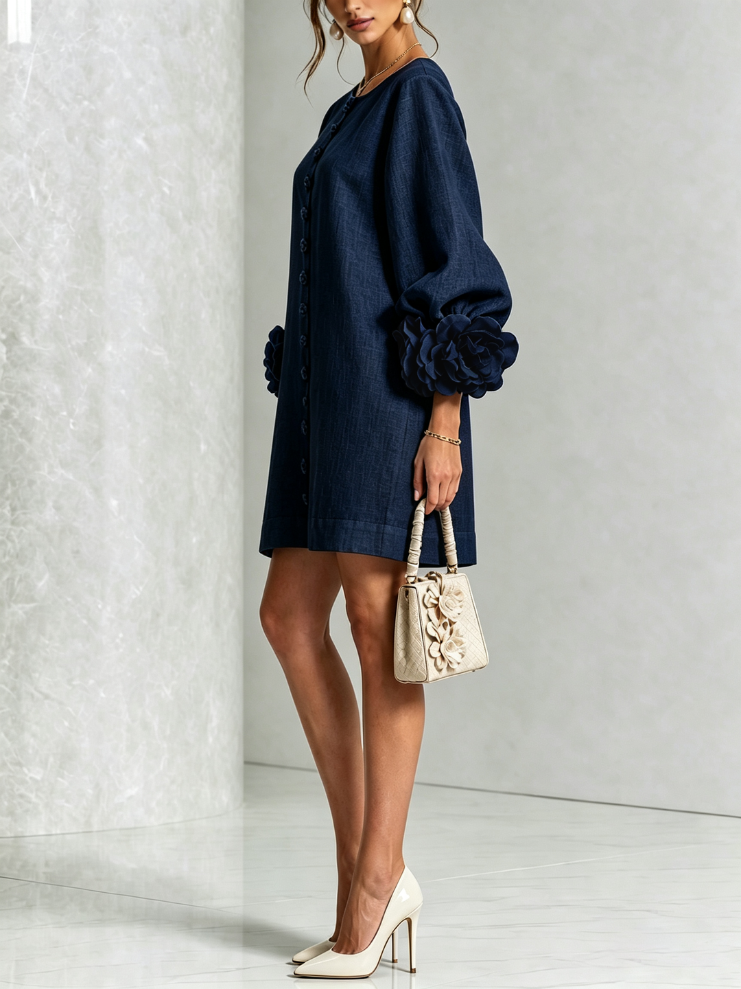 Side view of the navy shirt dress with flower buttons, puffed sleeve, and rosette cuff.