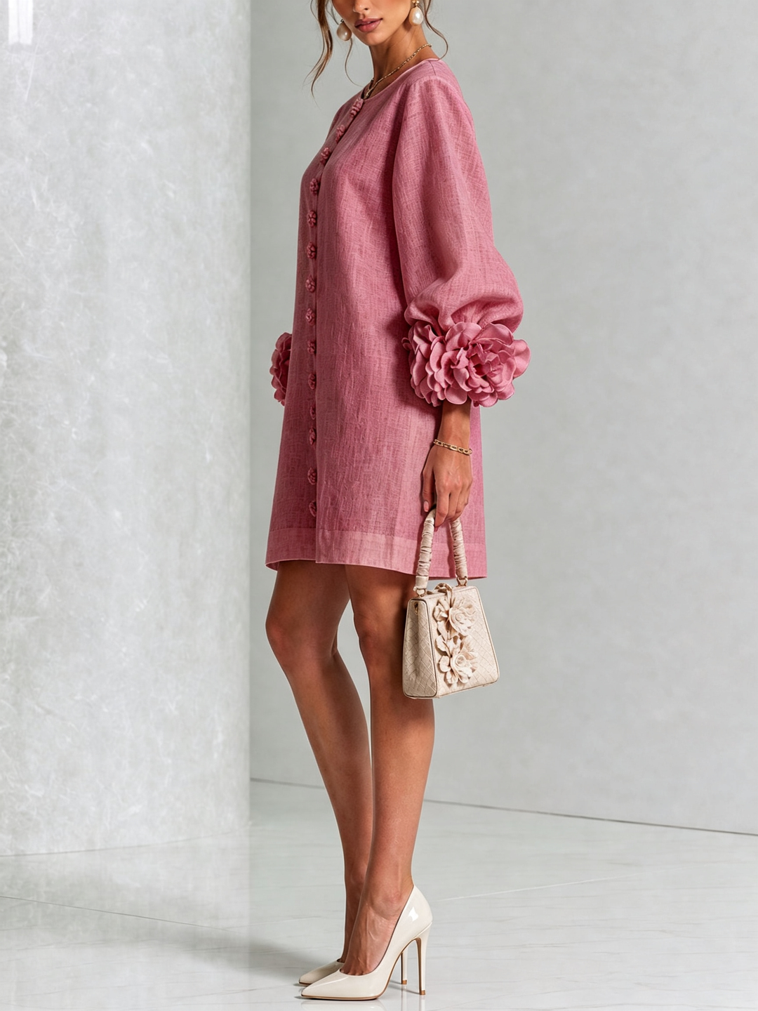 Side view of the pink dress on a model, showing the button row, puffed sleeve and rosette cuff. 45