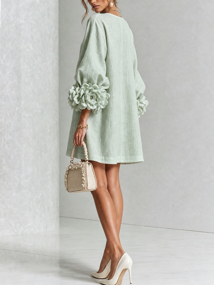 Back view of the mint green dress on a model, showing the plain back and flower-trimmed sleeve cuffs. 33