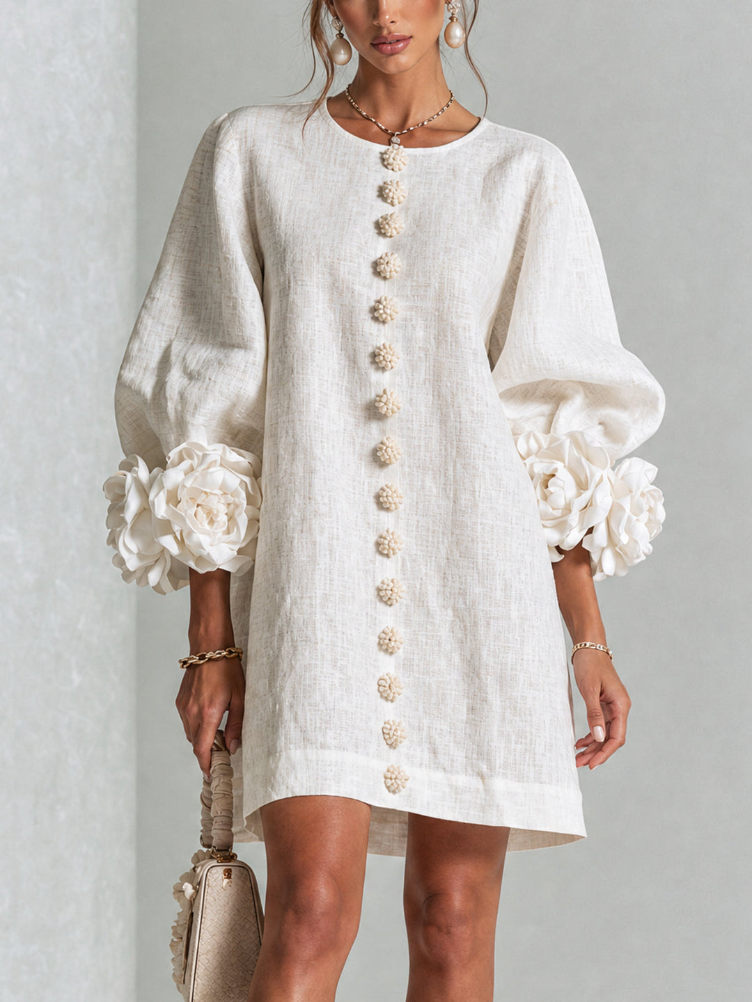 Beige A-line mini dress with floral buttons and voluminous sleeves, front view.