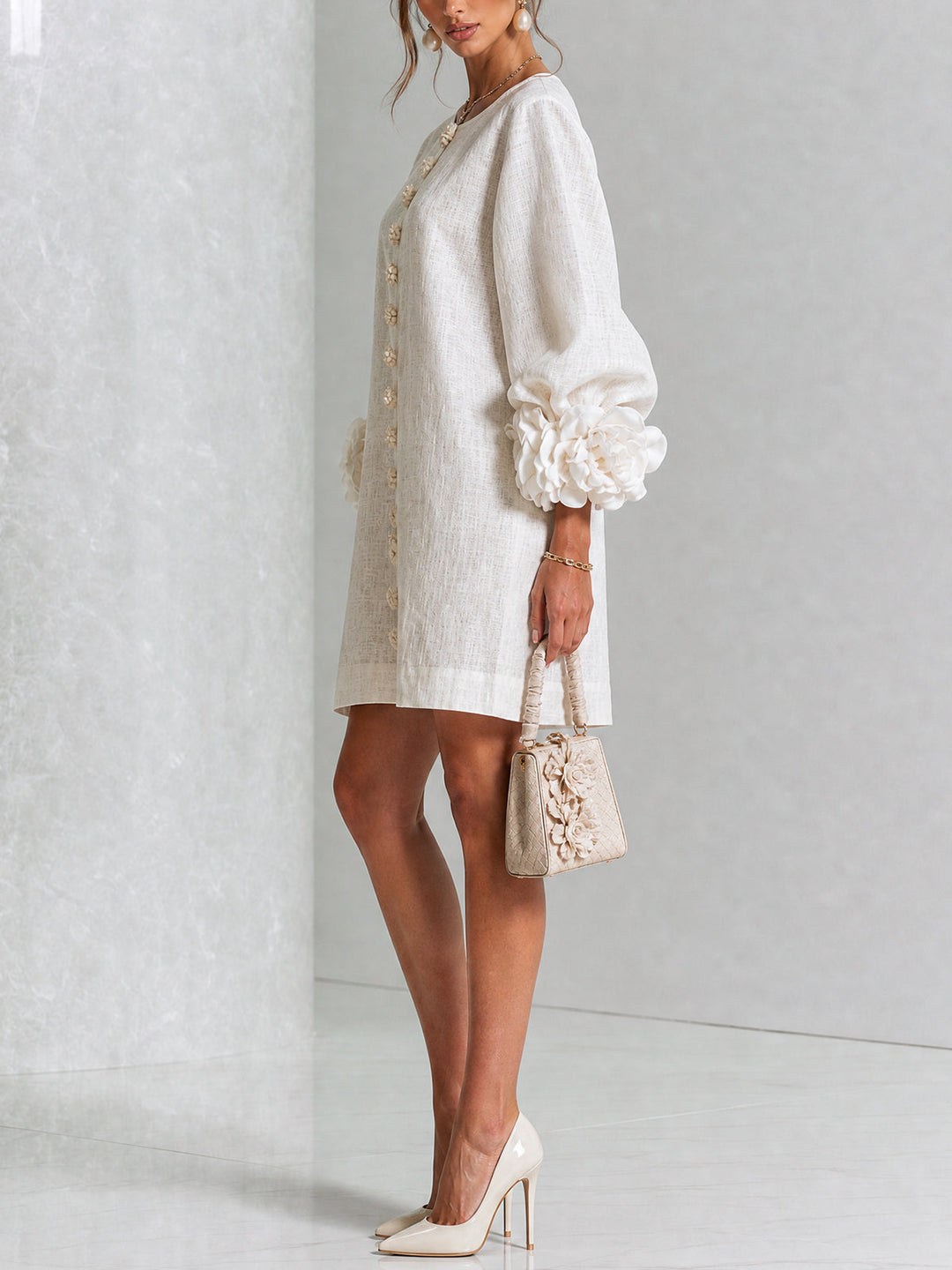 Beige linen mini dress, side detail with the rosette cuff and button placket visible.