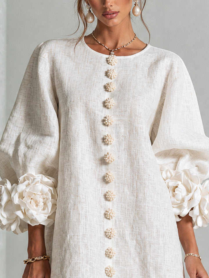 Close-up of the cream shirt dress bodice with round neckline, flower-shaped buttons, and oversized rose cuffs.
