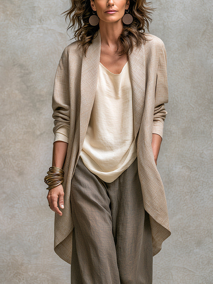 Close-up detail of the open shawl-collar cardigan with a curved hem layered over the cream top.